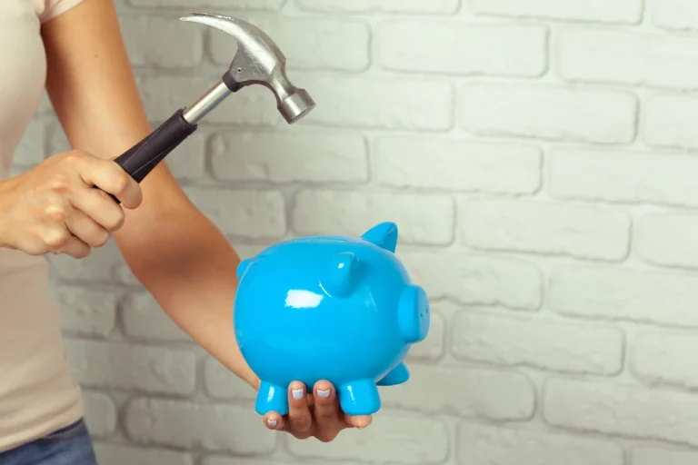 Une femme qui casse sa tirelire avec un marteau pour financer des travaux de rénovation