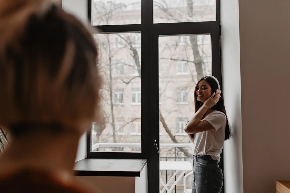 Une femme qui regarde par la fenêtre pour évaluer vis à vis appartement avant achat